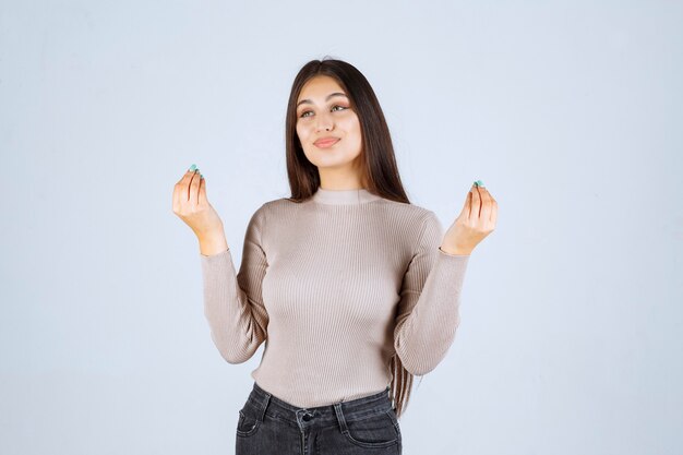 Menina de camisa cinza, desfrutando de algo.