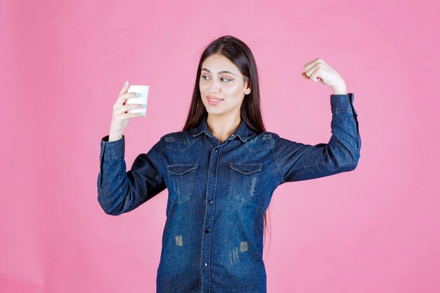 Menina de camisa jeans tomando uma xícara de café e se sentindo poderosa