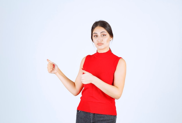 Menina de camisa vermelha aparecendo os polegares.