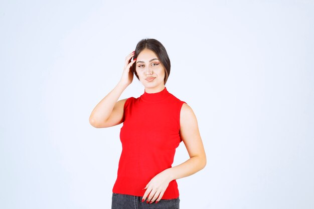 Menina de camisa vermelha dando poses neutras, positivas e atraentes.