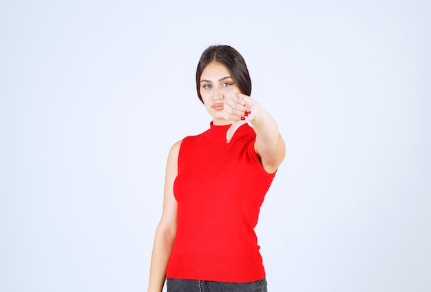 Menina de camisa vermelha, mostrando sinal de antipatia.