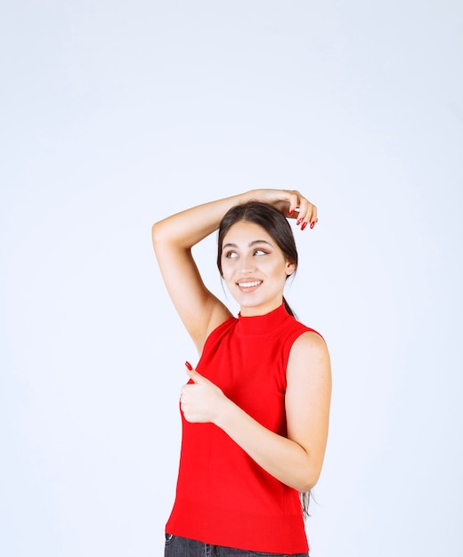 Menina de camisa vermelha, mostrando sinal positivo com a mão.