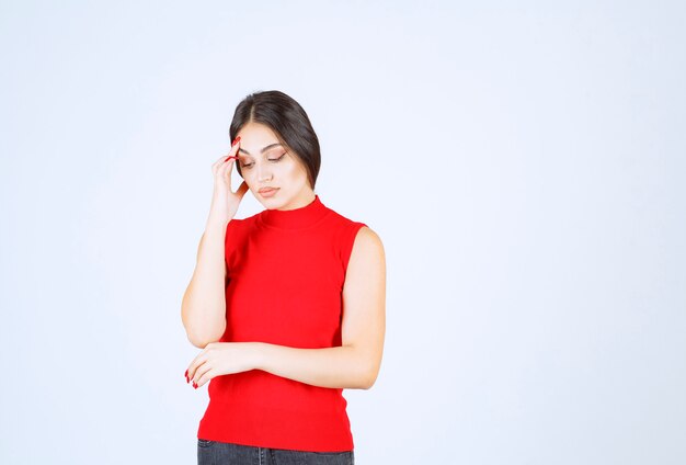 Menina de camisa vermelha parece triste e desapontada.