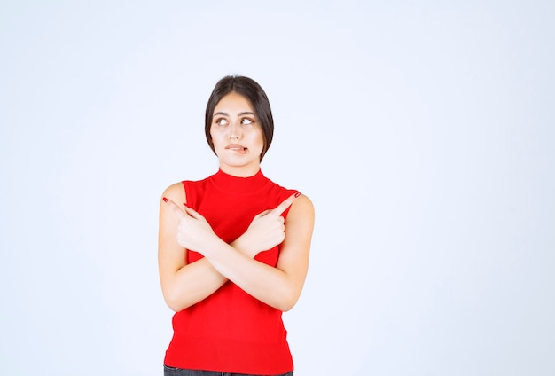 Menina de camisa vermelha parece triste e desapontada.