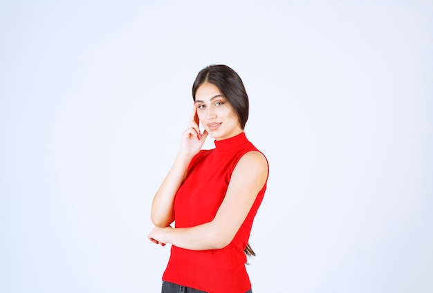 Menina de camisa vermelha, pensando e analisando.