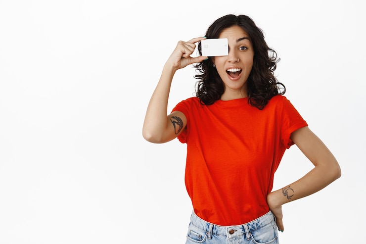Foto grátis menina de compras elegante, suspiro, mostra cartão de crédito e olha para descontos, comprando sem contato, pagando por algo, de pé sobre fundo branco