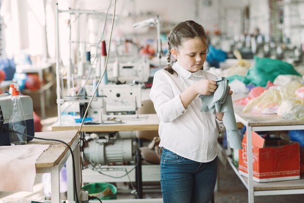 Menina de pé na fábrica com um fio