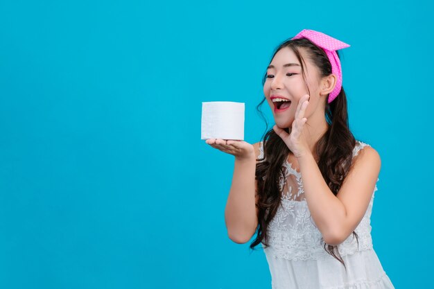 Menina de pijama branco, segurando um rolo de papel na mão no azul.