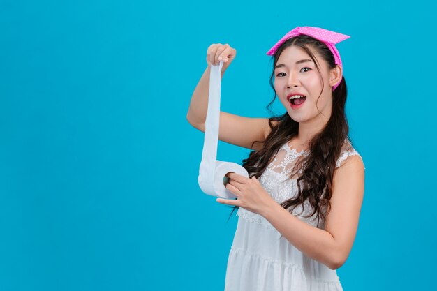 Menina de pijama branco, segurando um rolo de papel na mão no azul.