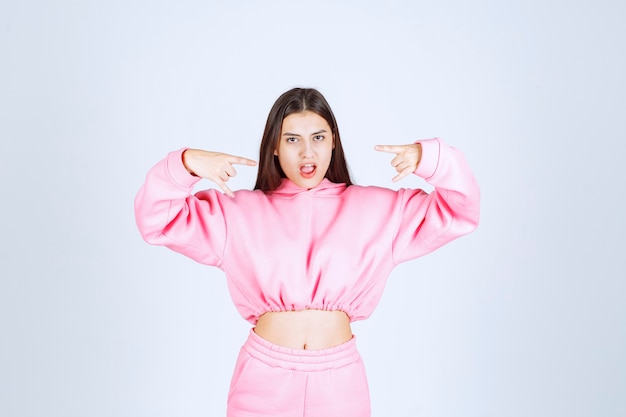 Menina de pijama rosa apontando para a boca