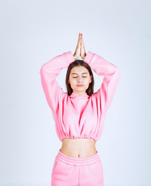 Menina de pijama rosa fazendo meditação
