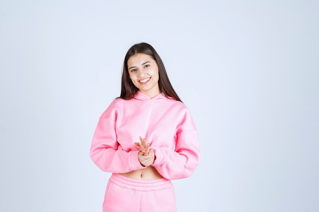 Menina de pijama rosa fazendo poses desagradáveis e alegres