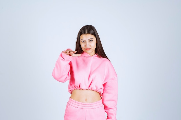 Menina de pijama rosa fazendo poses desagradáveis e alegres