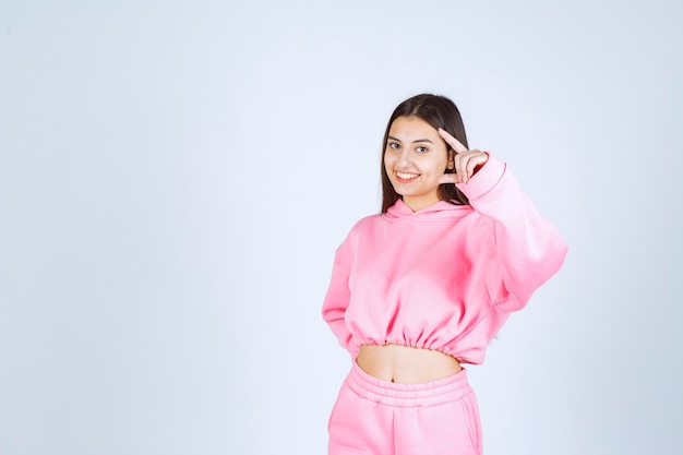 Menina de pijama rosa mostrando a quantidade ou tamanho estimado de um produto