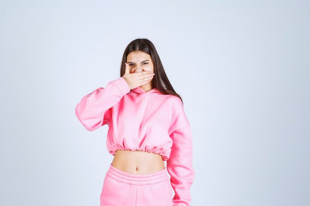 Menina de pijama rosa parece cansada e com sono