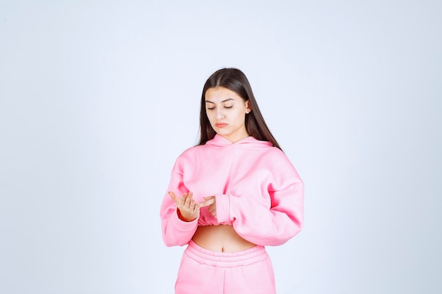 Menina de pijama rosa parece confusa e pensativa