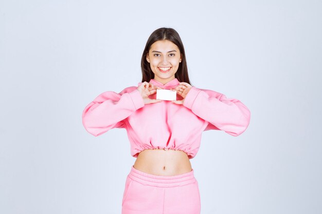 Menina de pijama rosa segurando um cartão de visita e se apresentando aos seus parceiros de negócios.