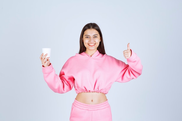 Foto grátis menina de pijama rosa segurando uma xícara de café e apreciando o sabor