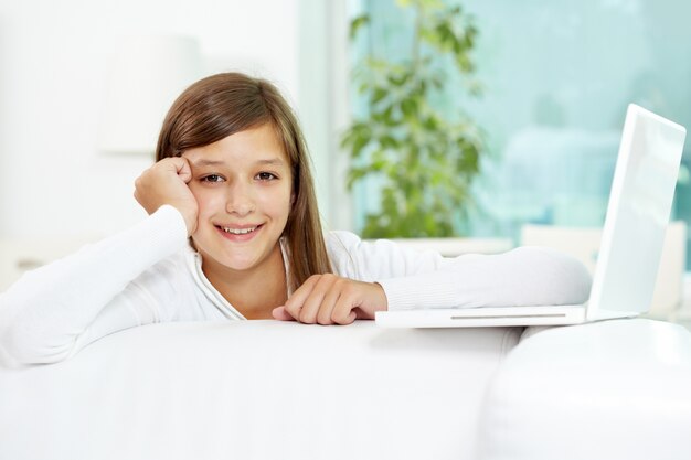 Menina de sorriso com um computador portátil