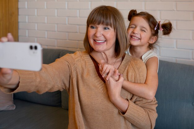 Menina de tiro médio e vovó tirando selfie