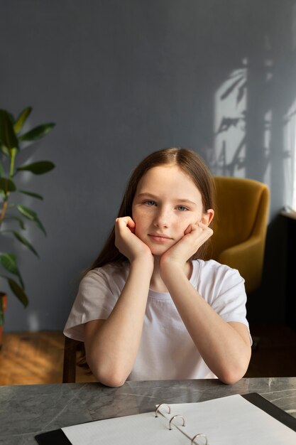 Menina de tiro médio sentada na mesa