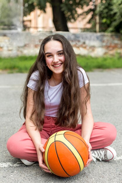 Menina de tiro no escuro, segurando uma bola de basquete fora