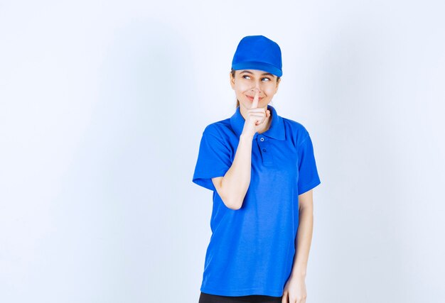 Menina de uniforme azul pedindo silêncio.