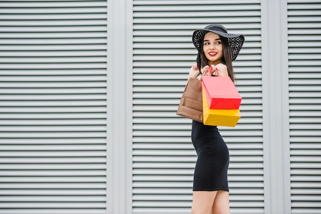 Menina de vestido preto com sacolas de compras