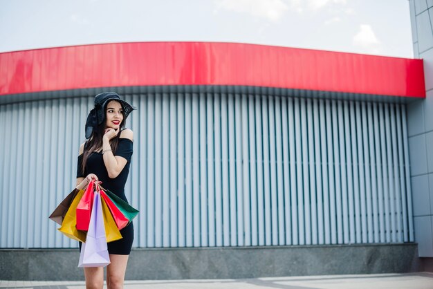 Menina de vestido preto com sacolas de compras