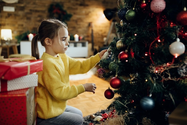 Menina decorando a árvore de Natal na sala de estar