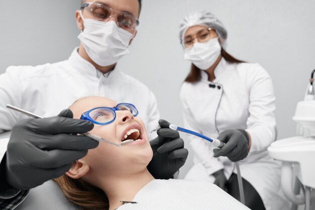 Menina deitada na cadeira do dentista enquanto médico curando os dentes