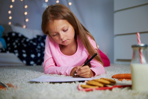 Foto grátis menina deitada na frente e escrevendo uma carta