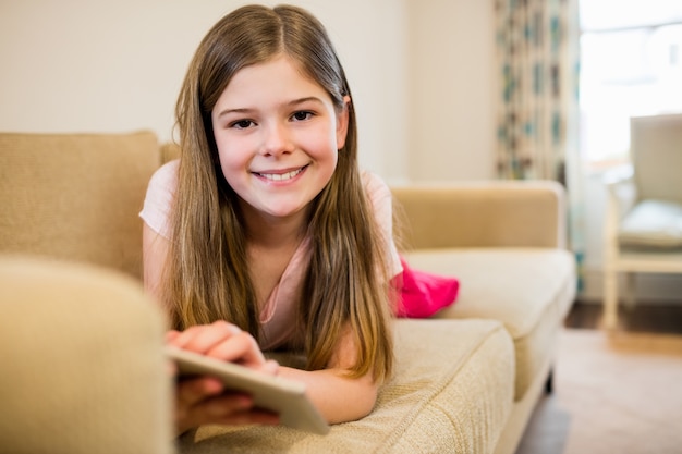 Menina deitada no sofá usando a tabuleta digital na sala de estar