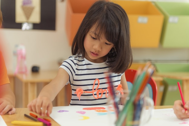 Menina desenhando lápis de cor na sala de aula do jardim de infância, conceito de educação pré-escolar e infantil, imagens de estilo Vintage Effective.