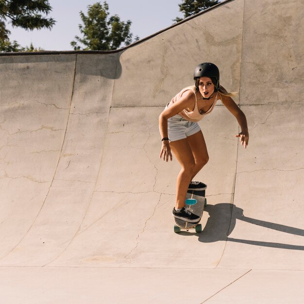 Menina desportiva com capacete de patinação na meia tubulação