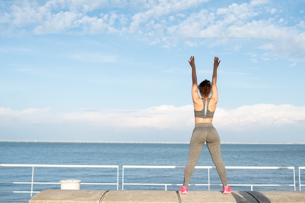 Menina desportiva que exercita no parapeito pelo rio