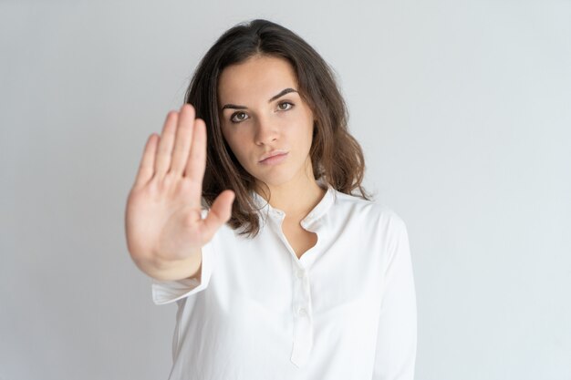 Menina determinada séria que mostra o sinal de parada.