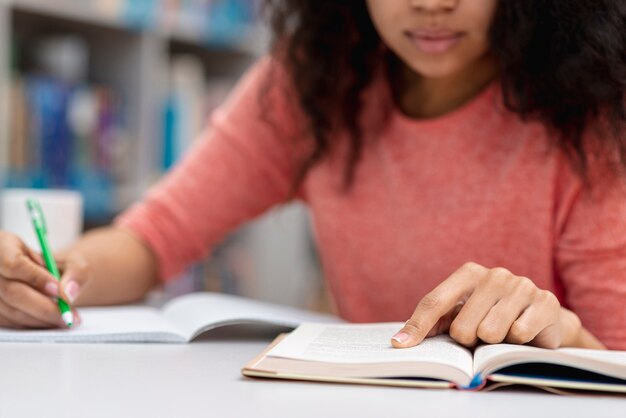 Menina do close-up que estuda na biblioteca