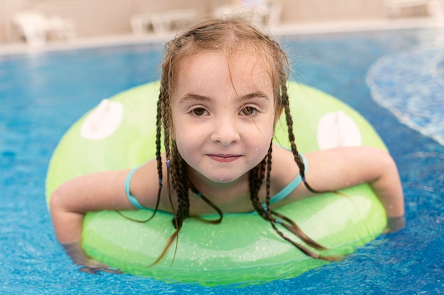 Menina do retrato no flutuador da piscina