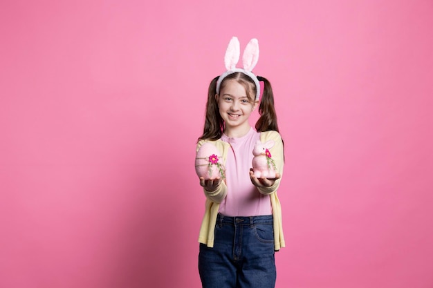 Foto grátis menina doce e festiva segurando decorações de páscoa e brinquedos fofinhos no estúdio