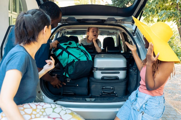 Menina e diversas pessoas saindo de férias, carregando malas de viagem no porta-malas do veículo. saindo em aventura de férias com a família e amigos, colocando mala ou carrinho no automóvel antes da viagem.