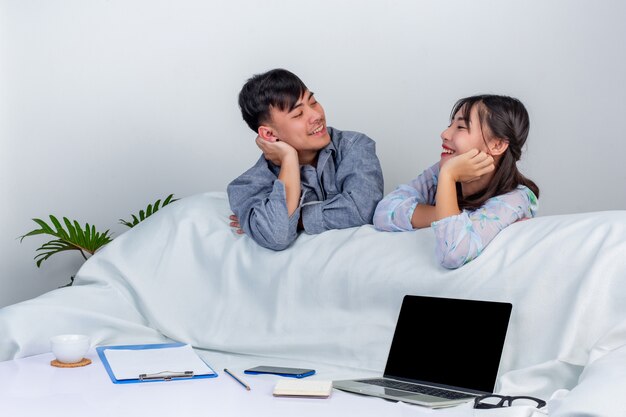 Menina e menino estão usando o labtop e aproveitam o tempo juntos por trás do sofá em casa.