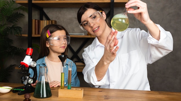 Menina e professora fazendo experiências científicas com microscópio