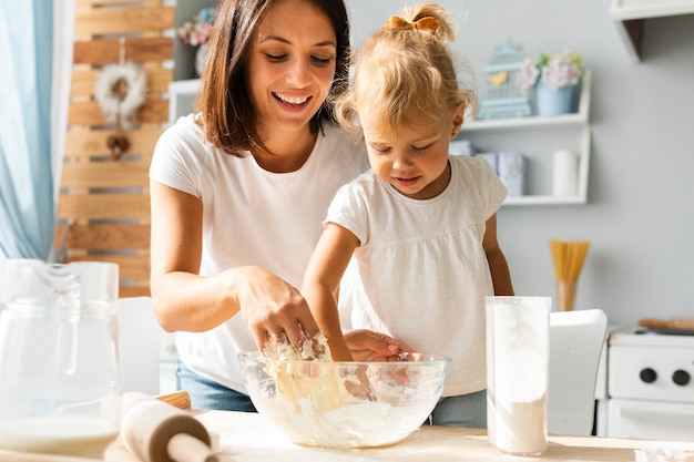 Menina e sua mãe preparando massa