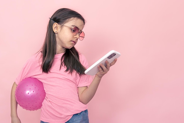 Menina elegante com um smartphone em um fundo rosa