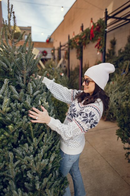 Menina elegante compra uma árvore de Natal.