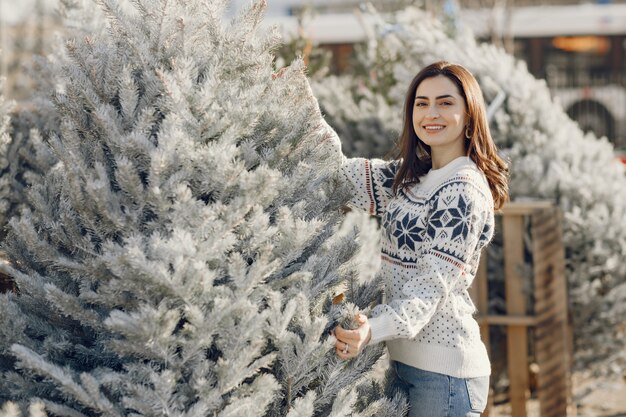 Menina elegante compra uma árvore de Natal.