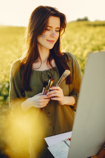 Menina elegante e bonita pintura em um campo