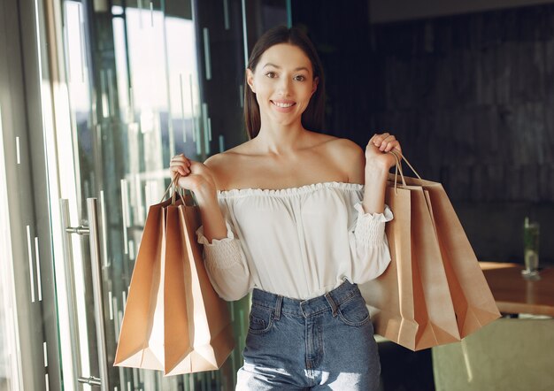 Menina elegante em pé em um café com sacolas de compras
