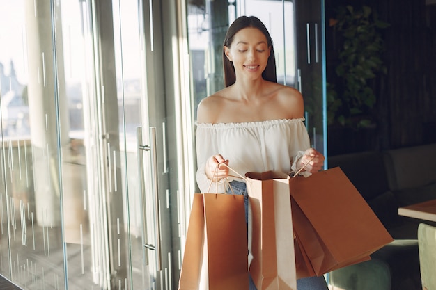Menina elegante em pé em um café com sacolas de compras